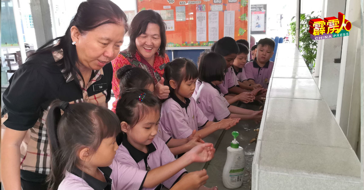 吴绣凤（后右起）和副校长陈慧芳，观察学生洗手，确保他们正确洗手。