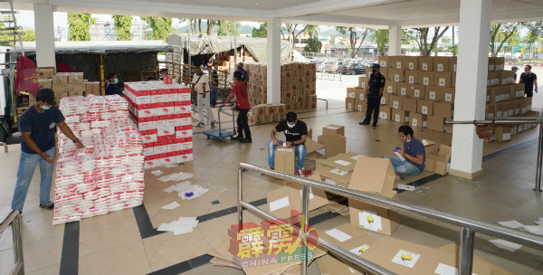 工作人员正忙碌黏封纸盒，方便置粮及密封，以加速包装工序。
