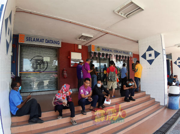 霹雳陆路交通局週三如常开放，一些市民戴着口罩在门外等候办理手续。