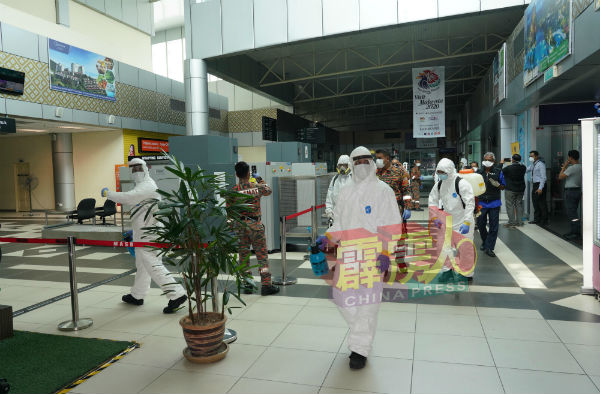 10名危险物品特别拯救部队队员，手持消毒喷雾身穿防护服地进入机场进行消毒工作。