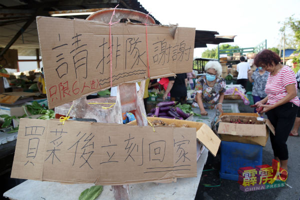 菜贩在摊位处挂上“请排队”、“买完就回家”等字眼的纸牌，希望民众能遵守管制令的规定。