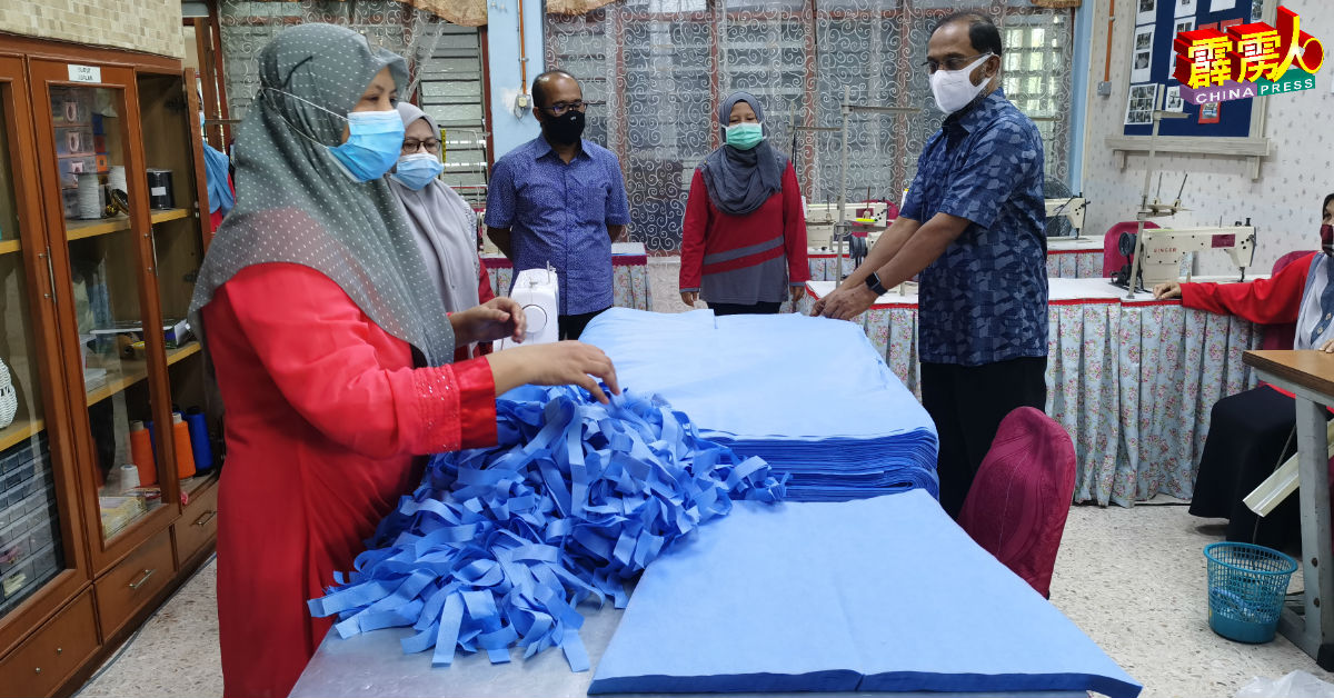 赞比里巡视曼绒社区发展局义工缝製个人防护服过程。