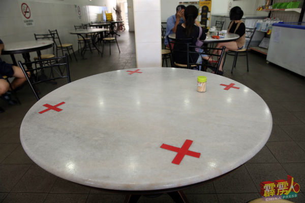 业者限定每张桌子人数，在桌上贴上禁止的打叉胶纸，让堂食顾客保持社交距离。