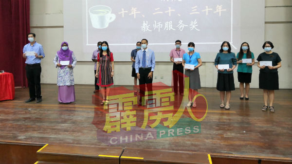 胡恩林（前排右起）在何家珍陪同下，颁发教师服务奖给服务10年、20年及30年的教师。