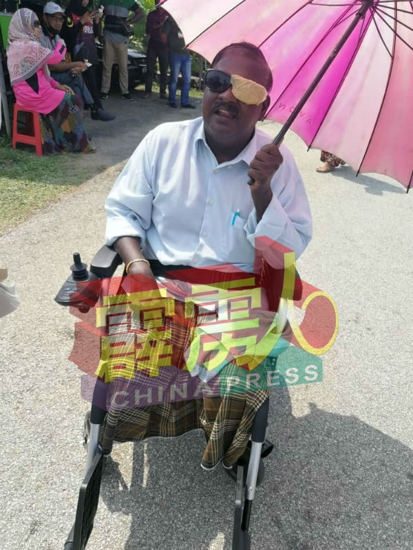 阿米鲁甘坐着电动轮椅、撑着伞、顶着热烈的太阳，独自前来仕林国小投票站投票，引起现场瞩目。