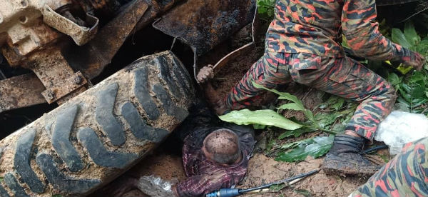 华裔司机脚部被夹在泥机底下，消拯员协助伤者脱困。（消拯局提供）