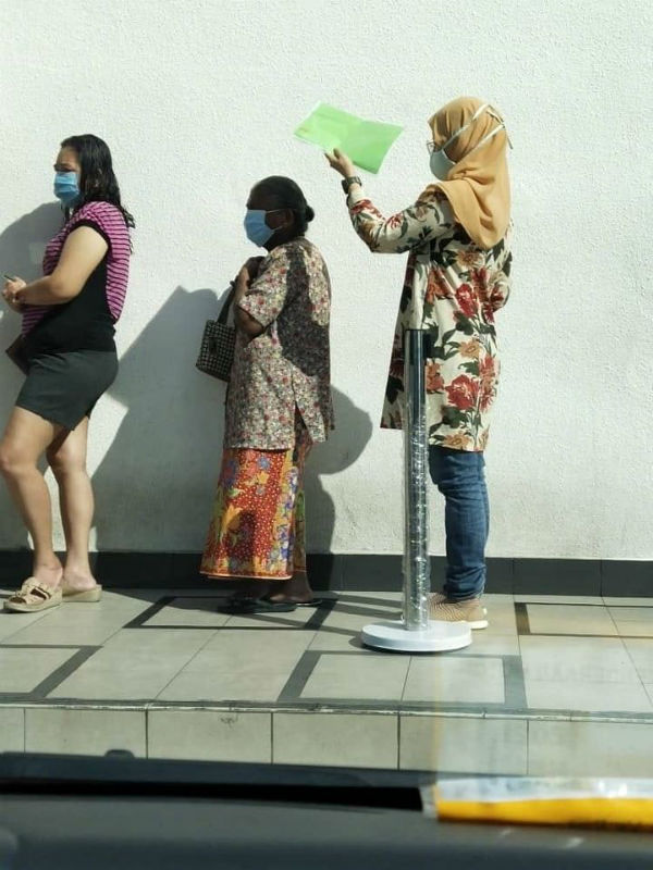 一名巫裔妇女在银行外排队等候时，以手中文人夹为排在前面的印裔老妇遮阳，其暖举获得网民赞扬。