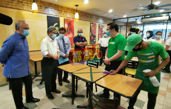 吉灵当Subway三明治连锁餐厅经理陈俊豪（右2）向鲁迈兹（左2）讲解该店营业前的消毒工程流程。