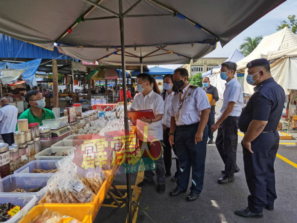 .刘国南（前排左2起）与怡保市政厅官员及警方巡视九洞露天巴剎小贩摊位。