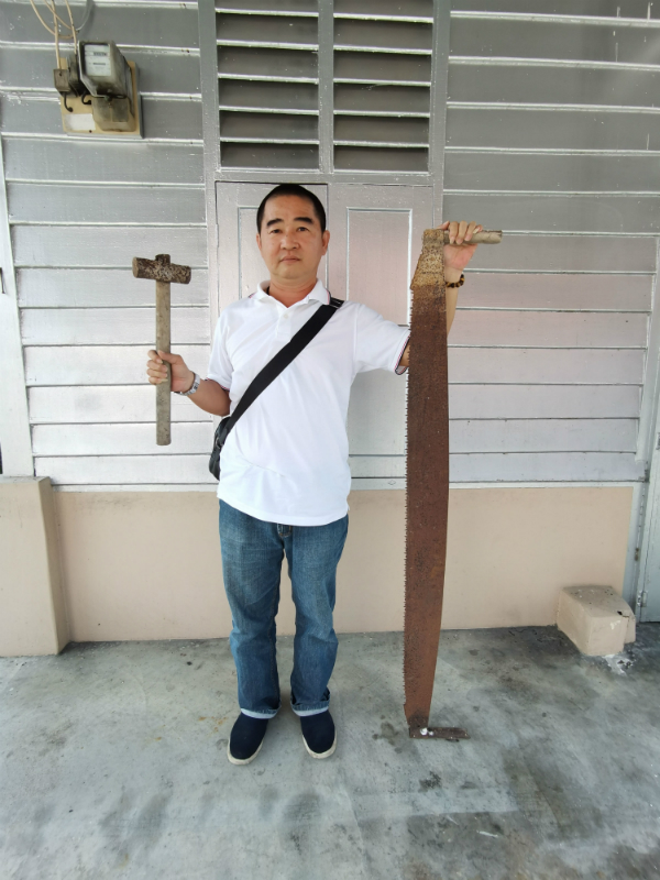 李祖赐展示祖父辈传下来的长木锯及铁锤，都有超过70年历史。