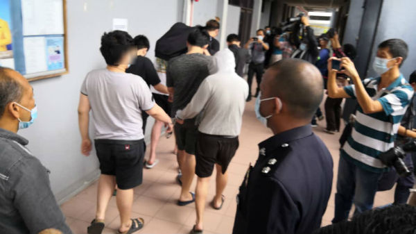8名涉及澳门骗局的华裔男子被带往法庭延扣。