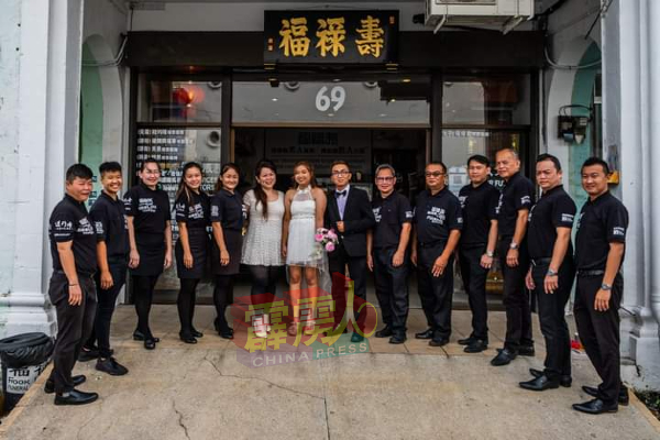 郑耀康（右7起）、王嘉欣夫妇与邓兆桢（左6）及同事，在寿板店前分享新婚喜税。