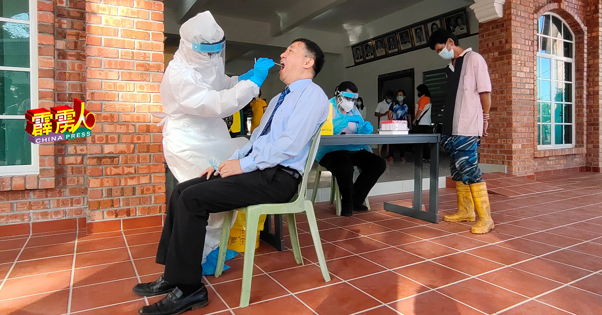 医务专员为崇华独中校长庄织华进行鼻喉拭子测试，该校园丁慕斯达化在后排队。