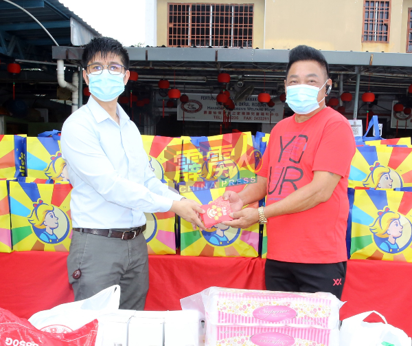 锺志伟（左）移交红包给霹雳怡保幸运之家残障儿童福利中心院长张国梁（右）。