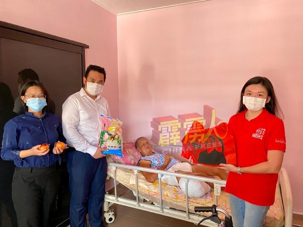 张嘉恩（左起）、张哲敏及古海燕，到也南新村派派发干粮福袋给予一名卧病在床的村民。