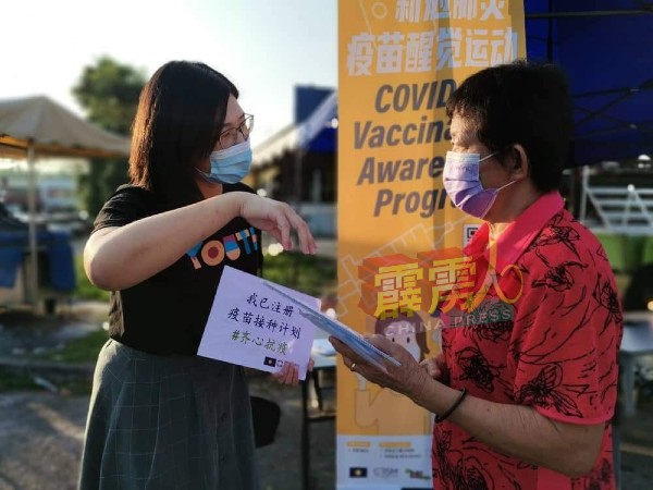 陈昭宋（左）向居民讲解接种新冠肺炎疫苗登记程序。