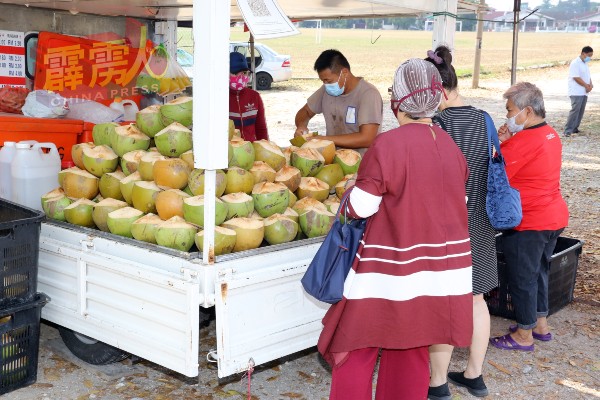 罗国辉的商业车置放了排得美美的椰子，应付大热天的需求。