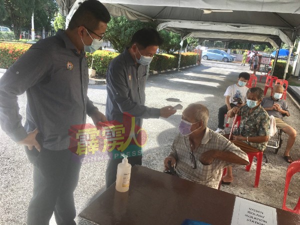 马华华都牙也县议员杨广发（左起）及梁智伟，协助长者报到接种疫苗。