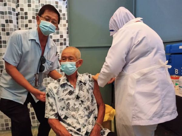 王雅霖（左）陪同乐龄人士接种疫苗，协助沟通工作。