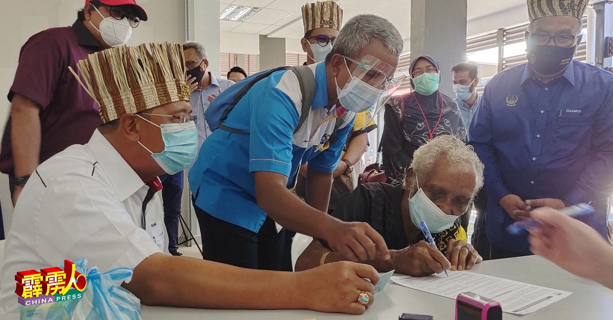 阿都拉曼（左）与其他官员协助年龄88岁的原住民长者阿隆（右2）填写登记疫苗接种资料。