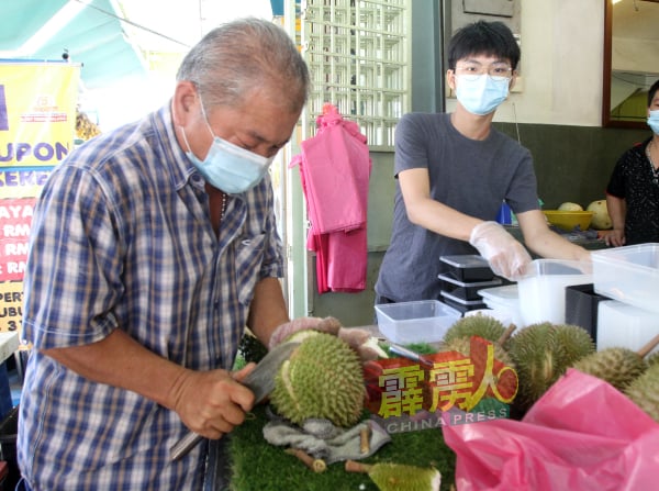 榴槤贩提供即开装盒的服务，让顾客回家就可品嚐。左为陈建春。