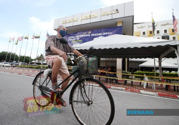 为了接种疫苗，73岁华裔老伯踏脚车骑了2公里，抵达英德拉慕丽亚体育馆疫苗接种中心。（自马新社）