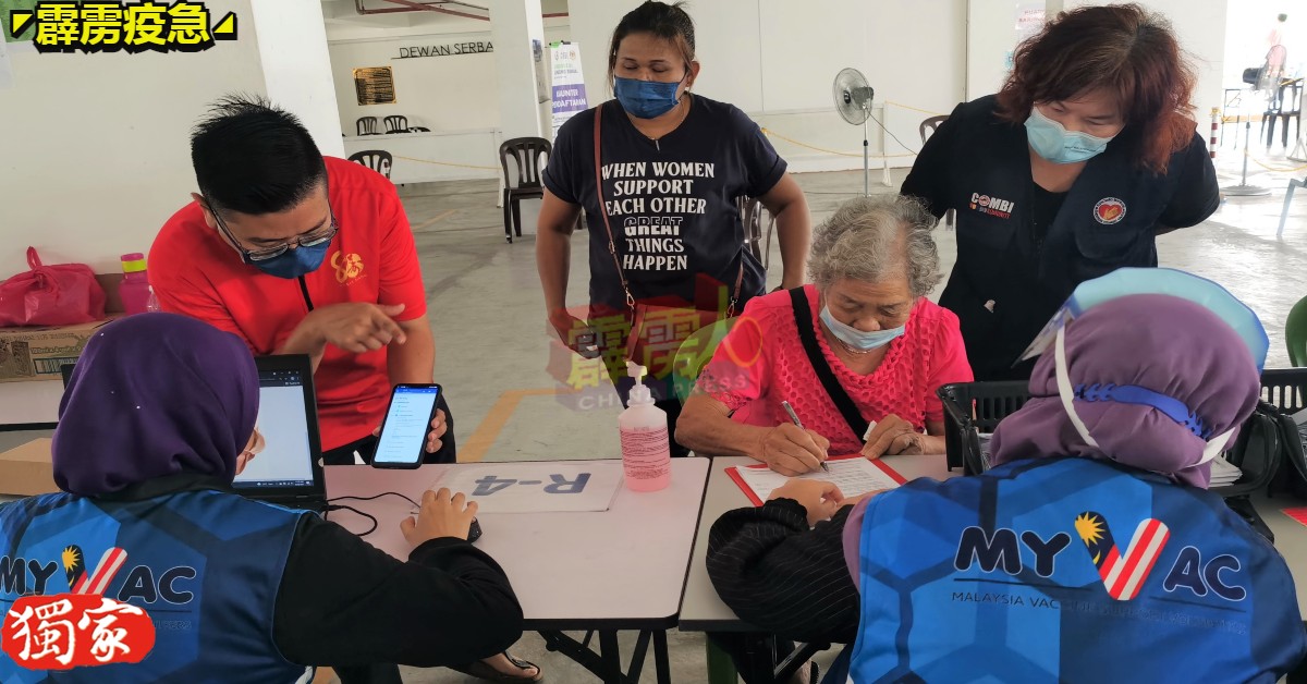 张宇晨（左站者）和黄丽娟（右站者）巡视曼绒疫苗接种中心，也为当场长者解说。