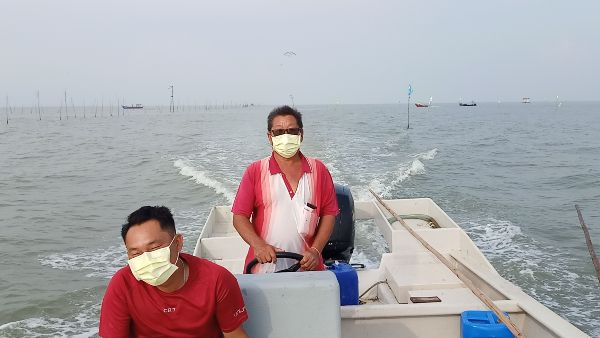 纪永利（左起）与林书进，以小船载着本报记者到海上蚶田（后方水域）捕捞。