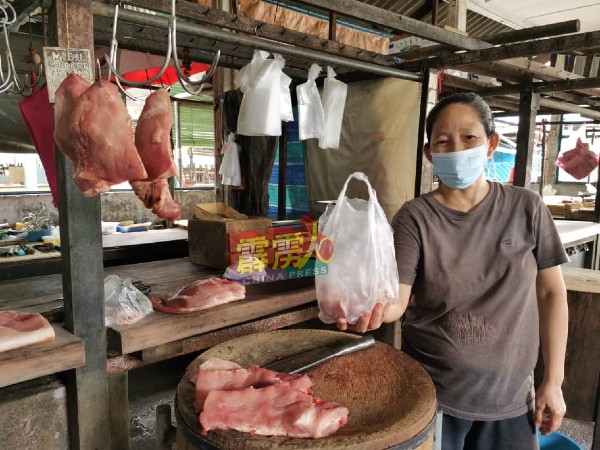 杨秋云展示顾客下单购买肉类后，彼此传递猪肉的方式，避免形成肢体接触。