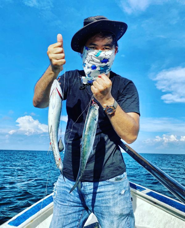 蔡耀梁在海上展示渔民钓获的硬尾鱼。