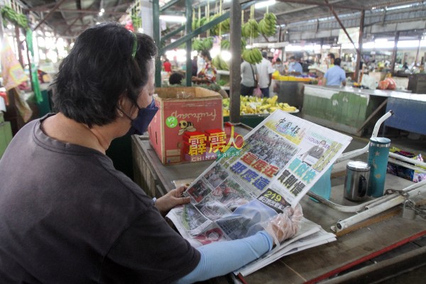 可能因没有顾客，这名小贩在阅读《中国报》跟进最新疫情和时局进展。