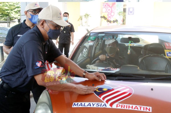 活动以得来速方式，为每辆媒体的轿车贴上“关怀马来西亚”国庆标语及国旗。