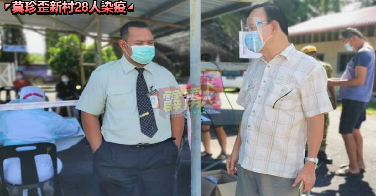 倪可汉（右）向站岗的卫生局医护人员瞭解莫珍歪新村“免疫社区外展计划”的实况。
