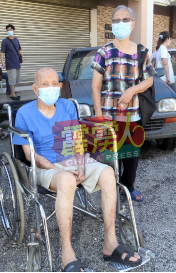 86岁的江春（坐在轮椅者）在妻子唐凤莲陪同下，前来接种疫苗。