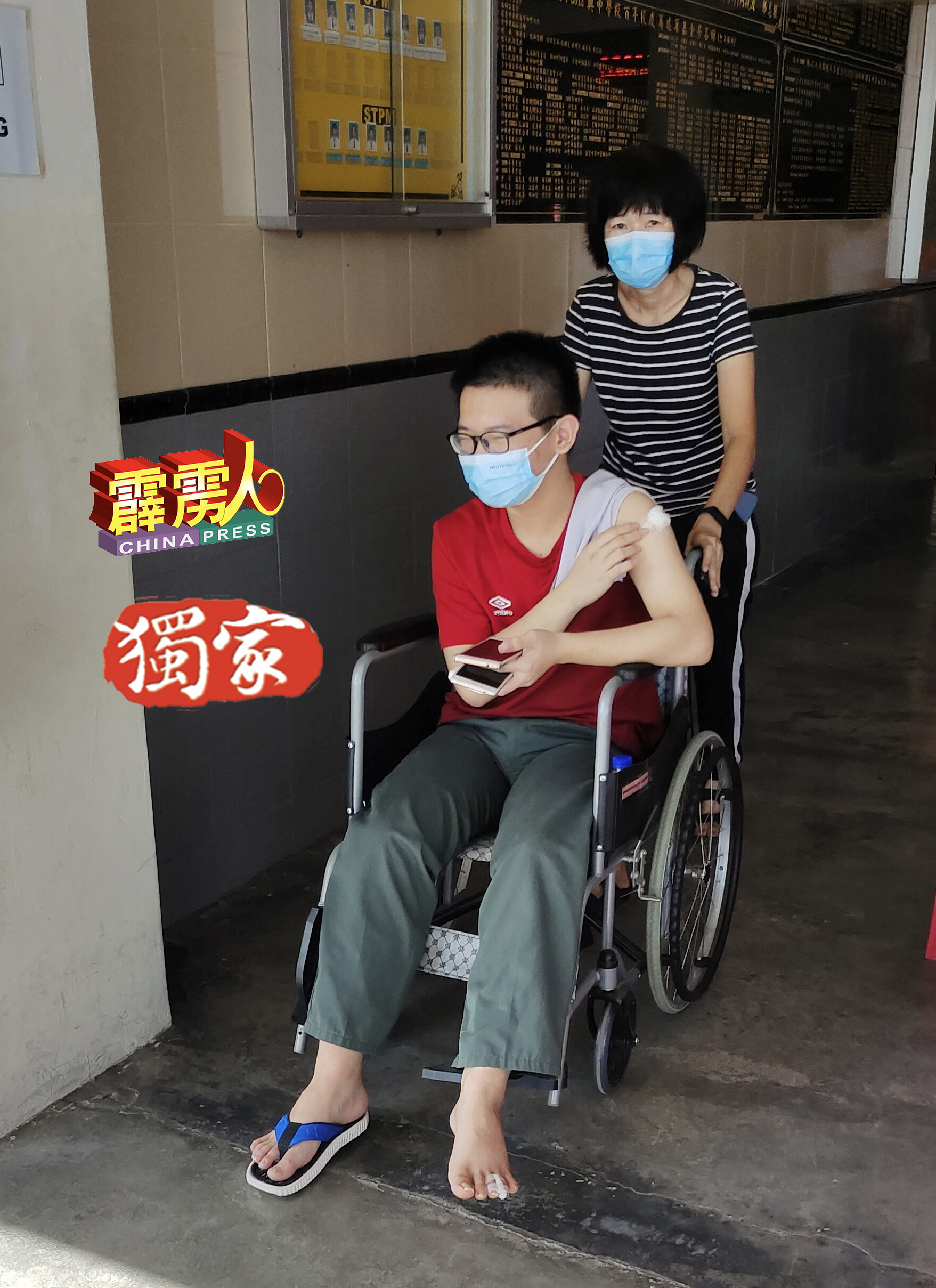 陈玉琴推着儿子陈德来离开礼堂。其儿子因走路不慎扭伤，被逼坐轮椅前来接种疫苗。