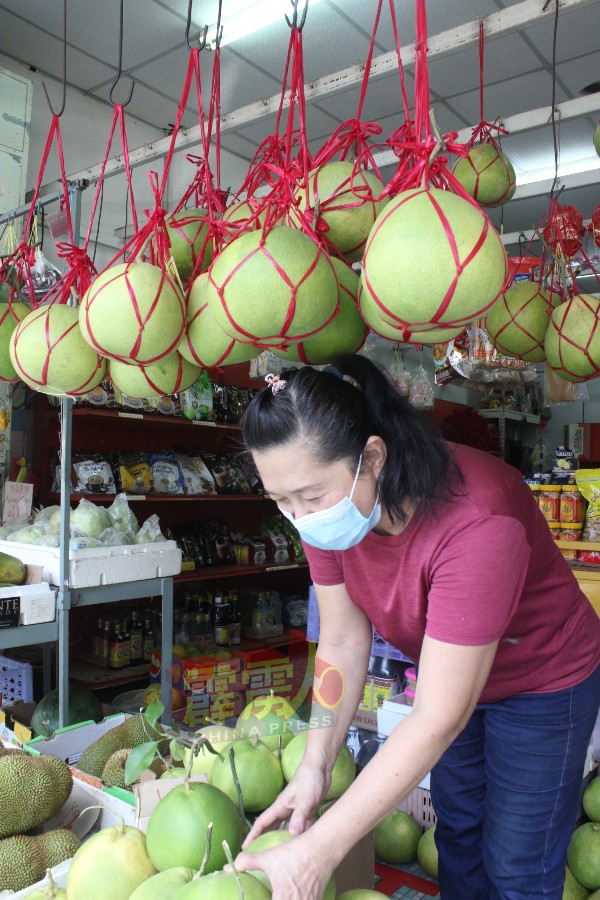 陈碧香（黄威记土产专卖店东主）整理土产店门前柚子。