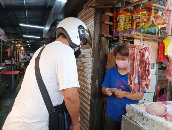 曹风儿（右起）移交猪肉给顾客。