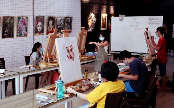 温紫彤（中）专注教导学生作画。