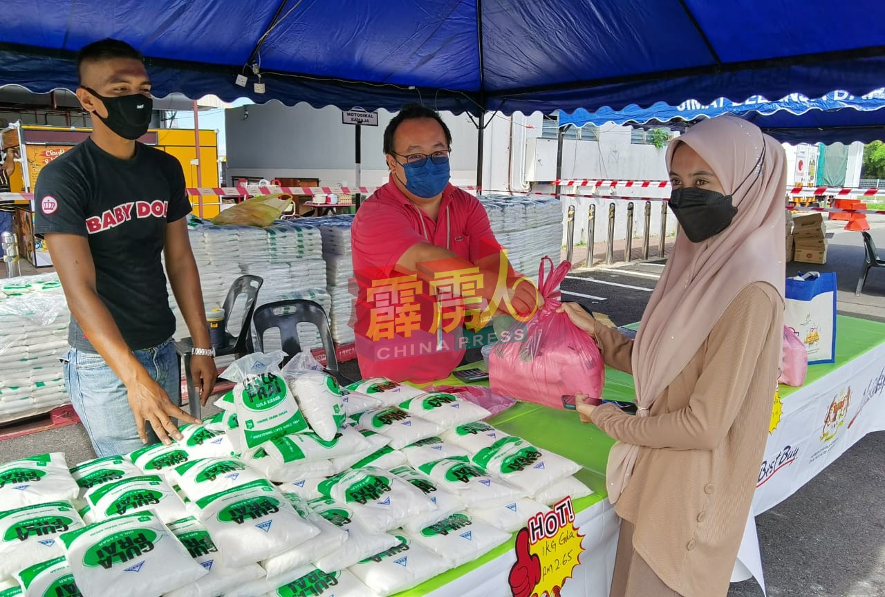 刘泓维（左2）忙于售卖白糖给消费者。