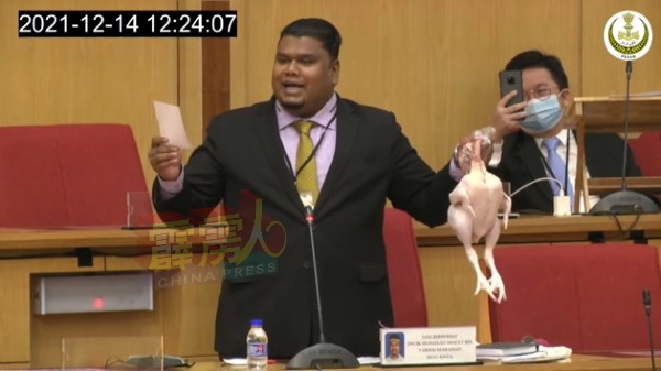莫哈末阿拉法携带肉鸡进入州议会，不仅引人瞩目，在其身后的周锦欢也忍不住举起手机拍摄。