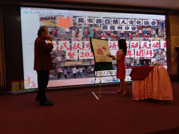 张桂娃（右）在张雅诰口琴伴奏下，熟练的绘画牡丹图。