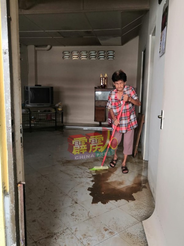 梁玉兰于水灾后，清理家中的积水。