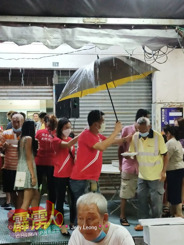 雨天带来极大不便，怡保王家班伙伴手撑雨伞，为长者们遮挡风雨。