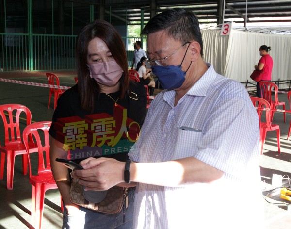 苏建祥（右起）为1名民众，检查其MySehjatera上的资讯。