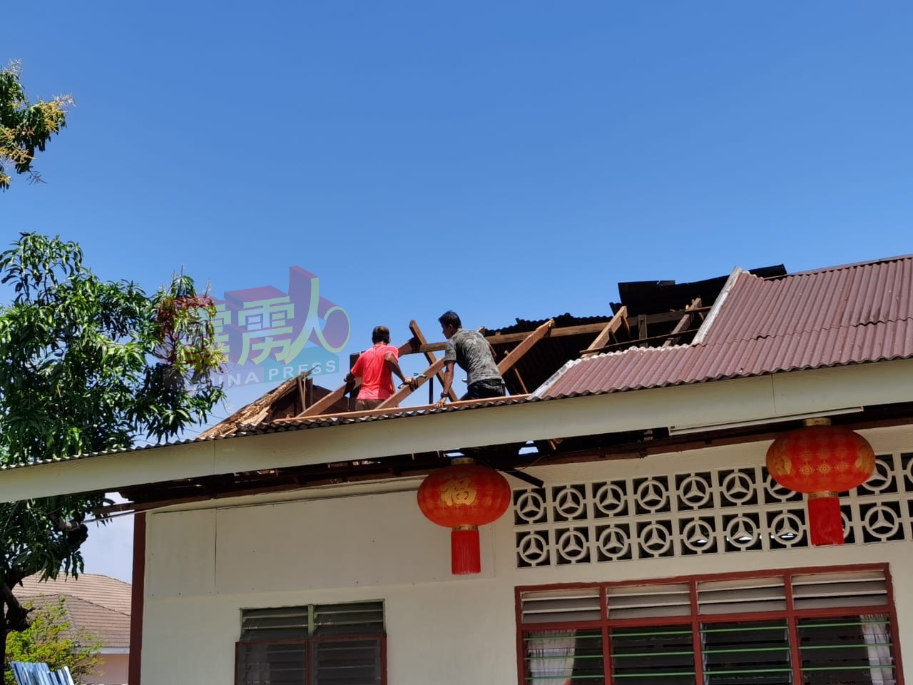 一些工作人员忙于维修被大风吹毁的屋顶。