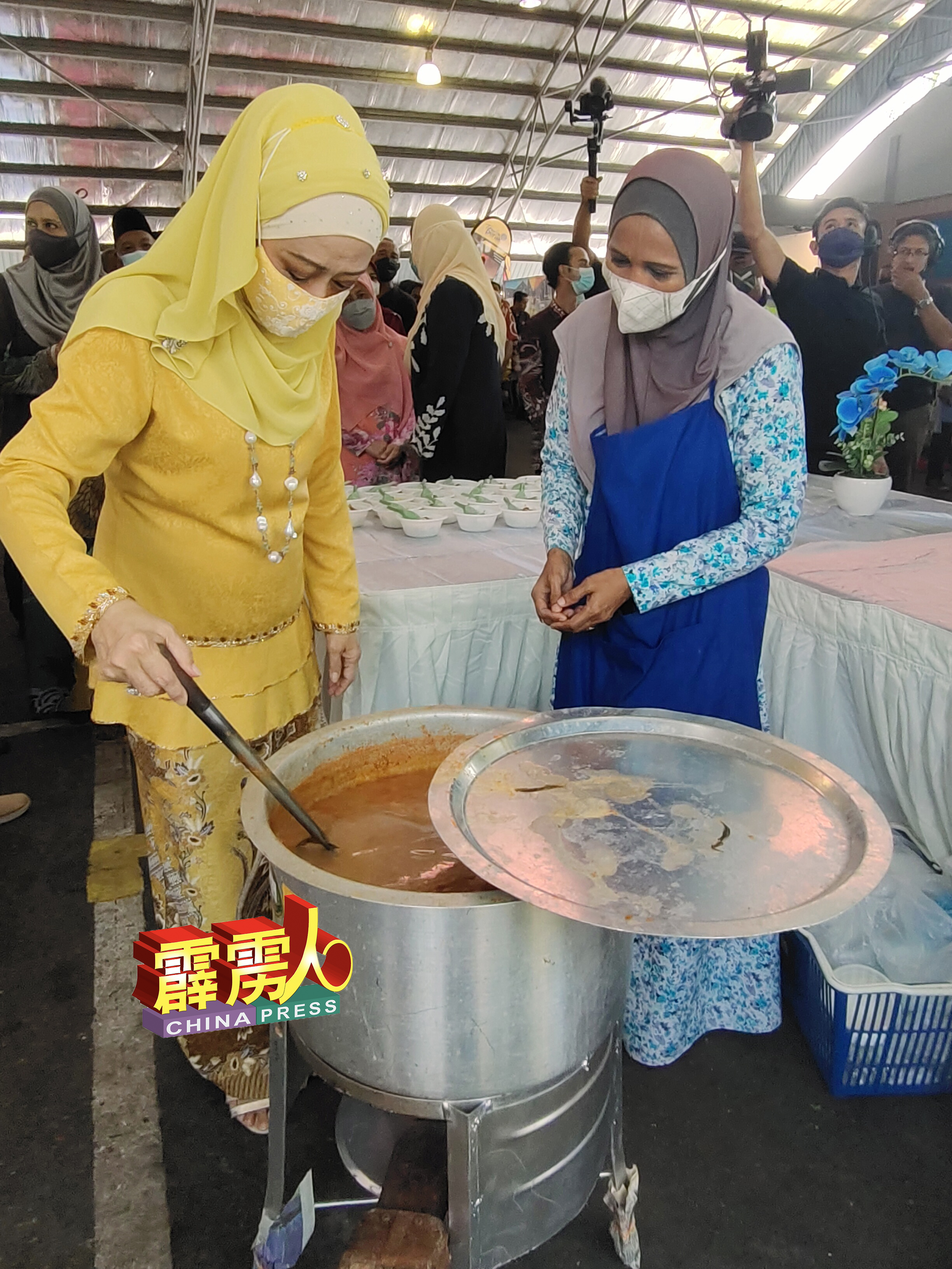 霹雳州王储妃纳扎都西玛（左）参观叻沙摊位时，亲自向小贩讨教煮好叻沙汤底的秘诀。