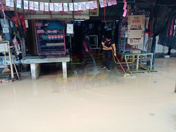 积水消退后，业者清洗商店堆积的淤泥和污水。