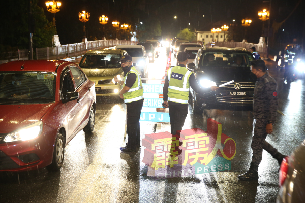 陆路交通局执法人员在细雨下，在波士打律设下路障截查车辆。