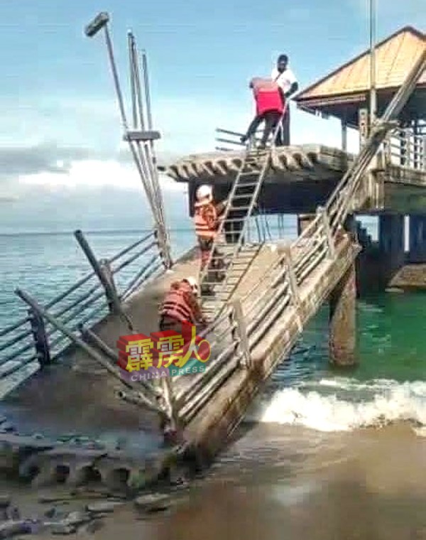 消拯员待退潮后，在塌陷在岸边的桥梁断层和末端的海上桥梁间，架上楼梯让受困夫妇沿着楼梯爬下。