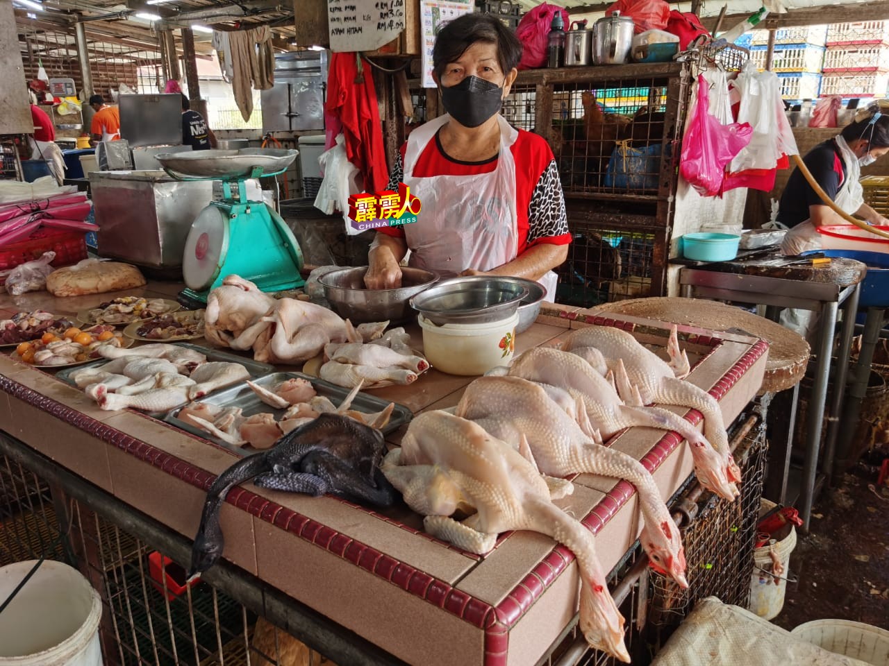 刘宝珍指鸡肉起价，市场冷清，摊上仍有很多鸡未卖出。